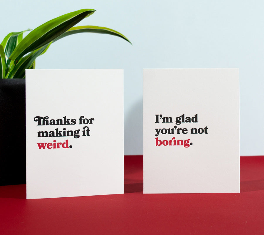 Two letterpress greeting cards with black and red text on white paper. Card 1: Thanks for making it weird. Card 2: I'm glad you're not boring.