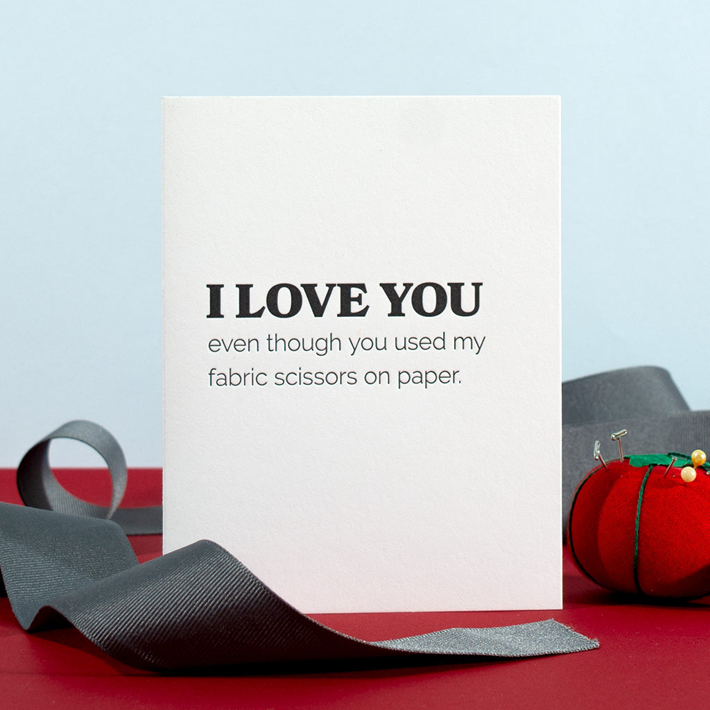 Greeting card with black text letterpress printed on white paper. I love you even though you used my fabric scissors on paper.
